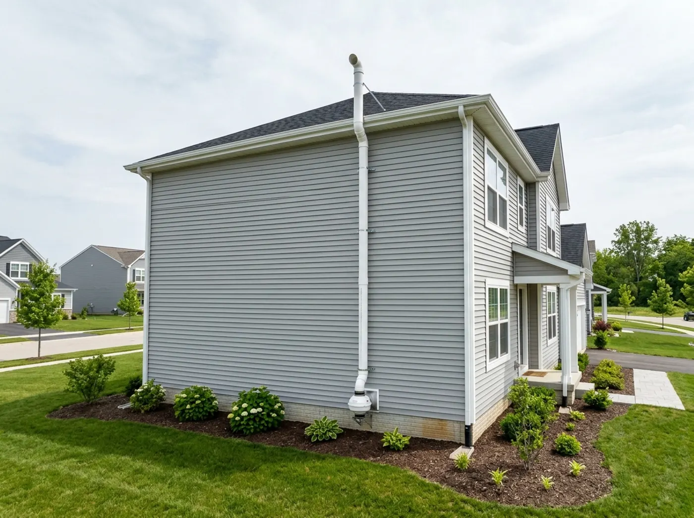 A radon vent pipe running up the exterior wall of a newly built Midwest house